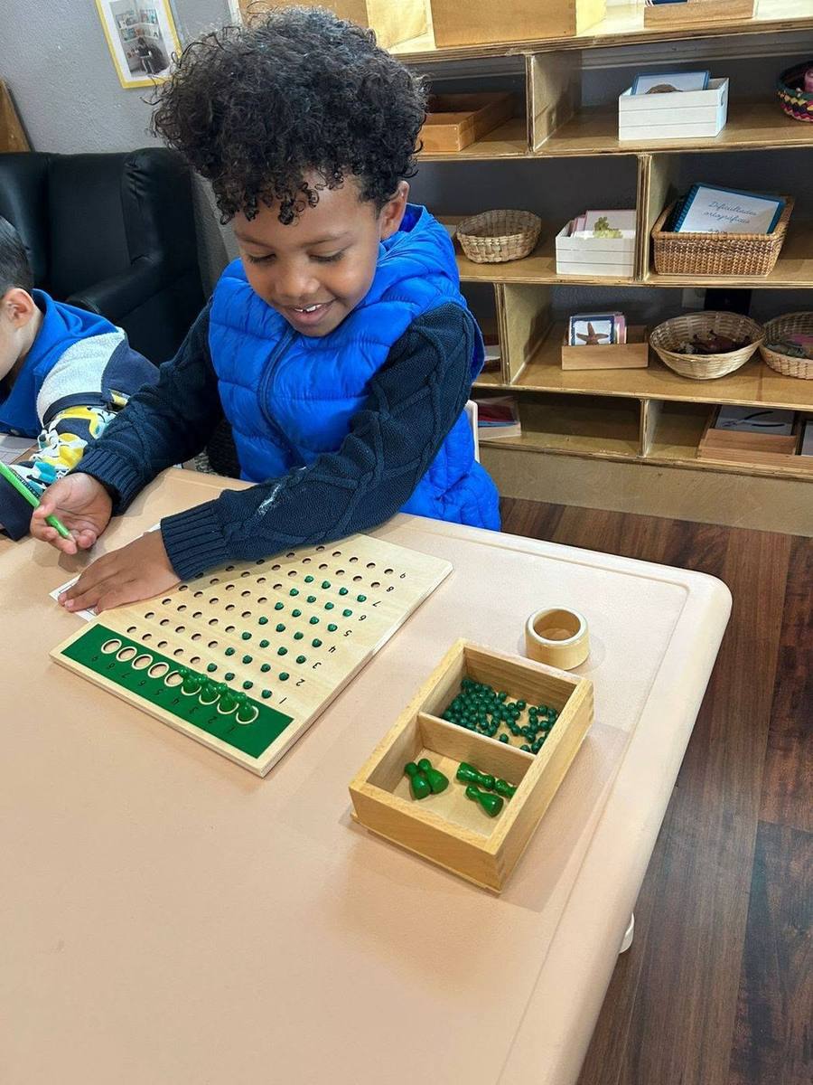 A smiling child works with a multiplication bead board