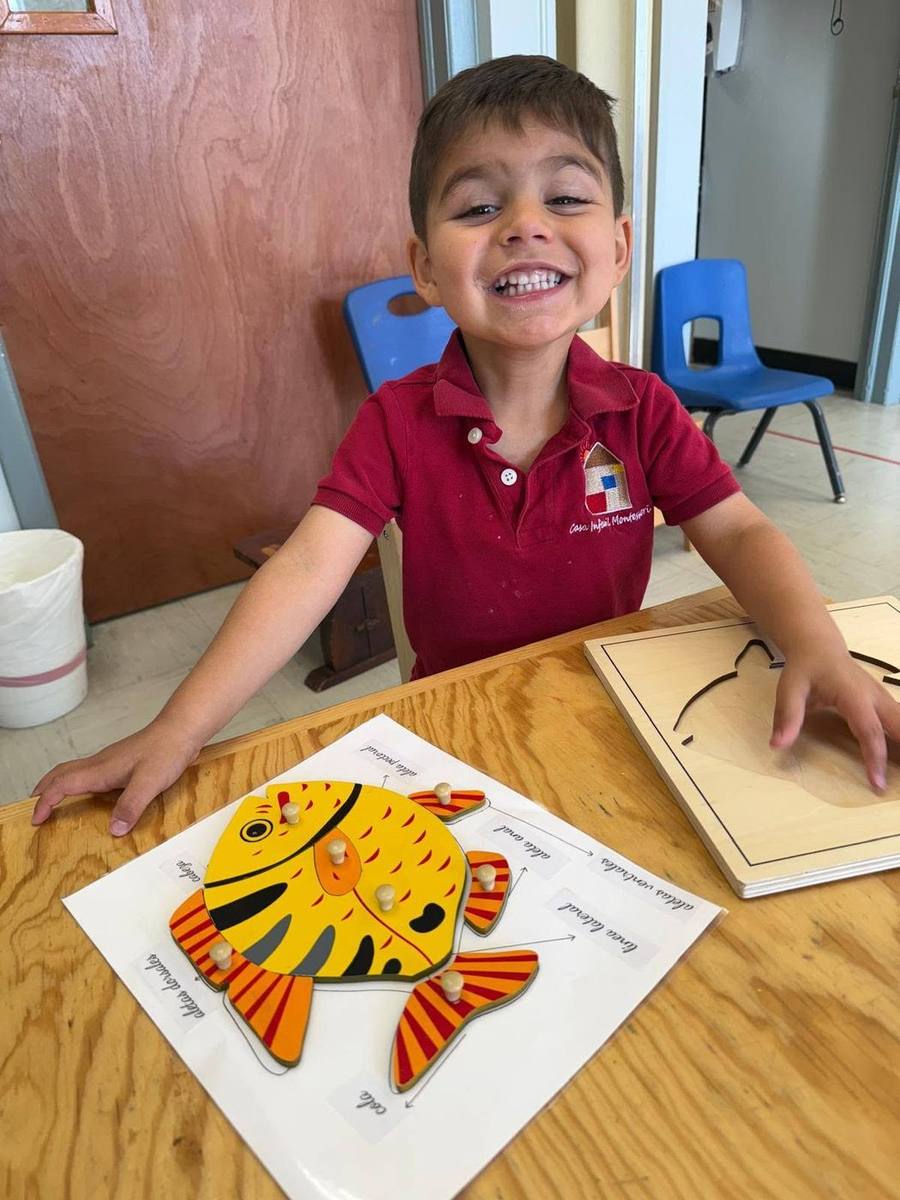 A smiling child finishes the parts-of-a-fish puzzle