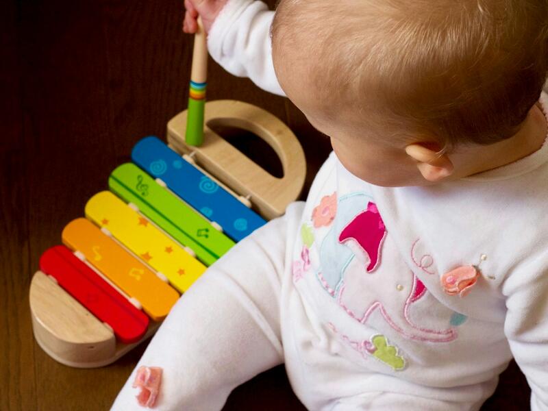 A baby plays with a wooden xylophone