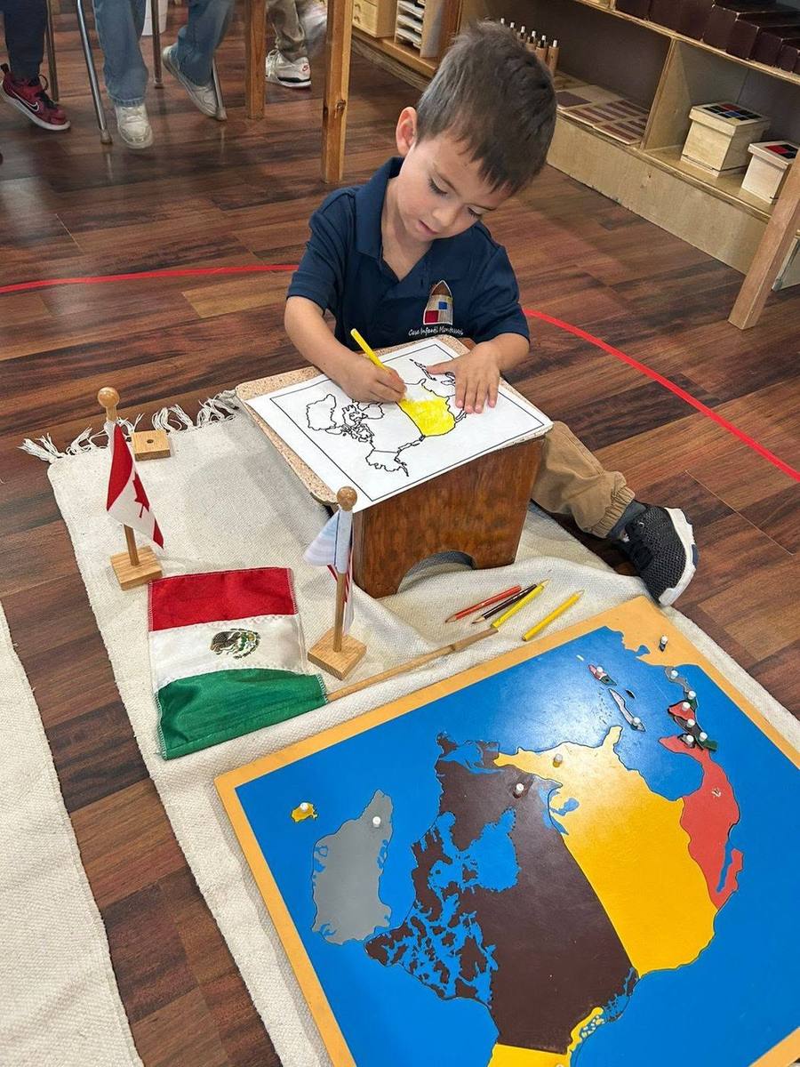 A child colors a map of North America beside the puzzle map and flags