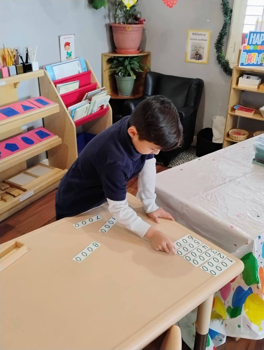 An elementary student lays out number cards into the thousands