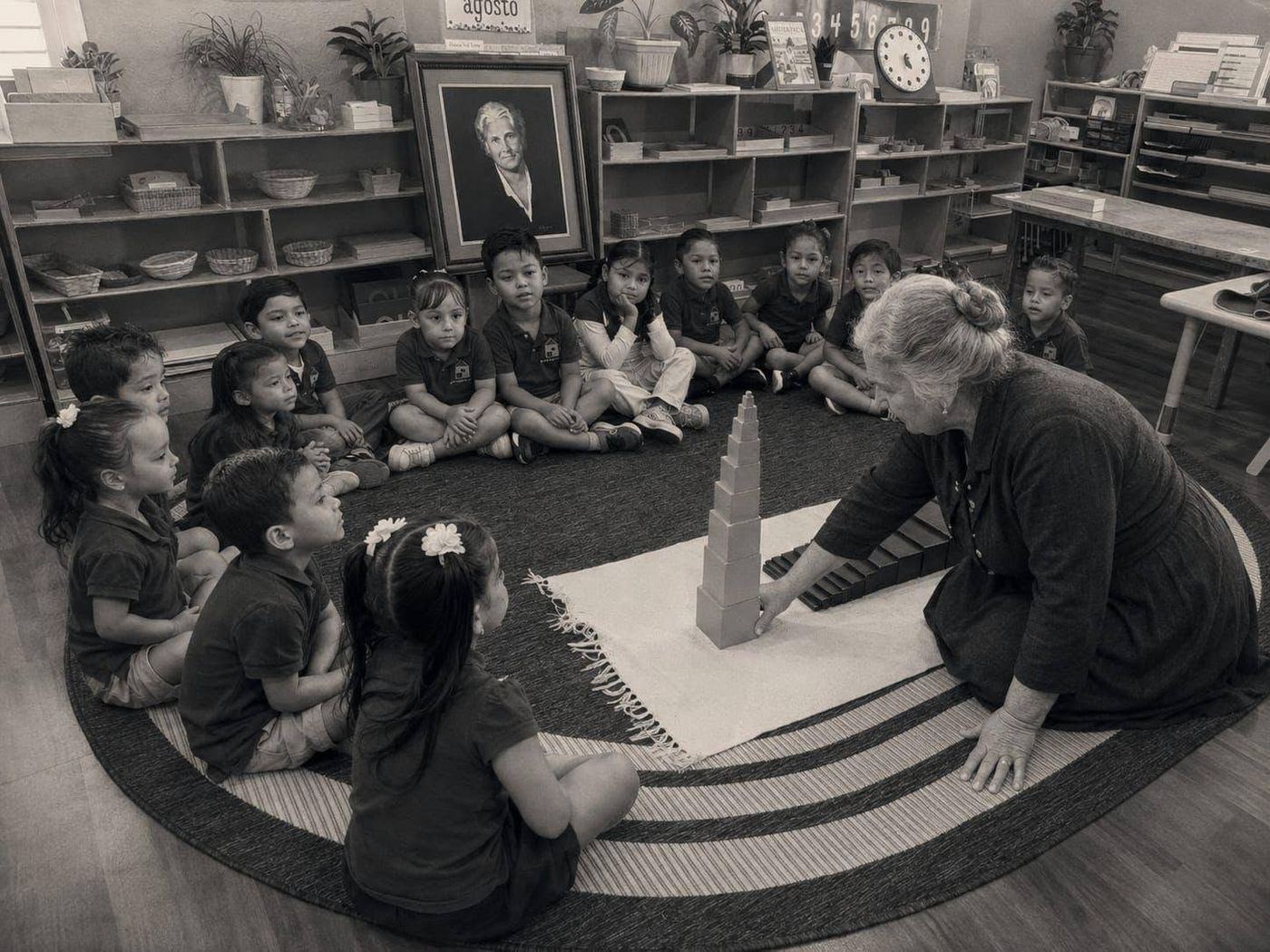 A guide presents the Pink Tower to a circle of children